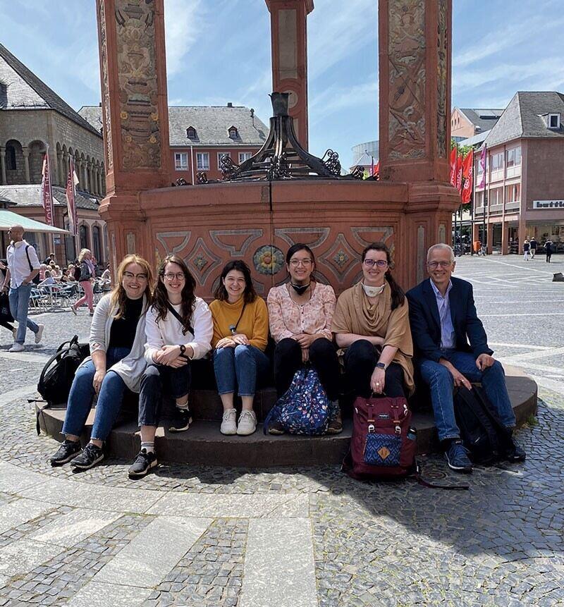 A group poses for a picture by a well in a town square.