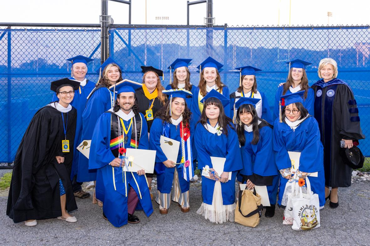 A group of students and teachers pose in the their graduation regalia.