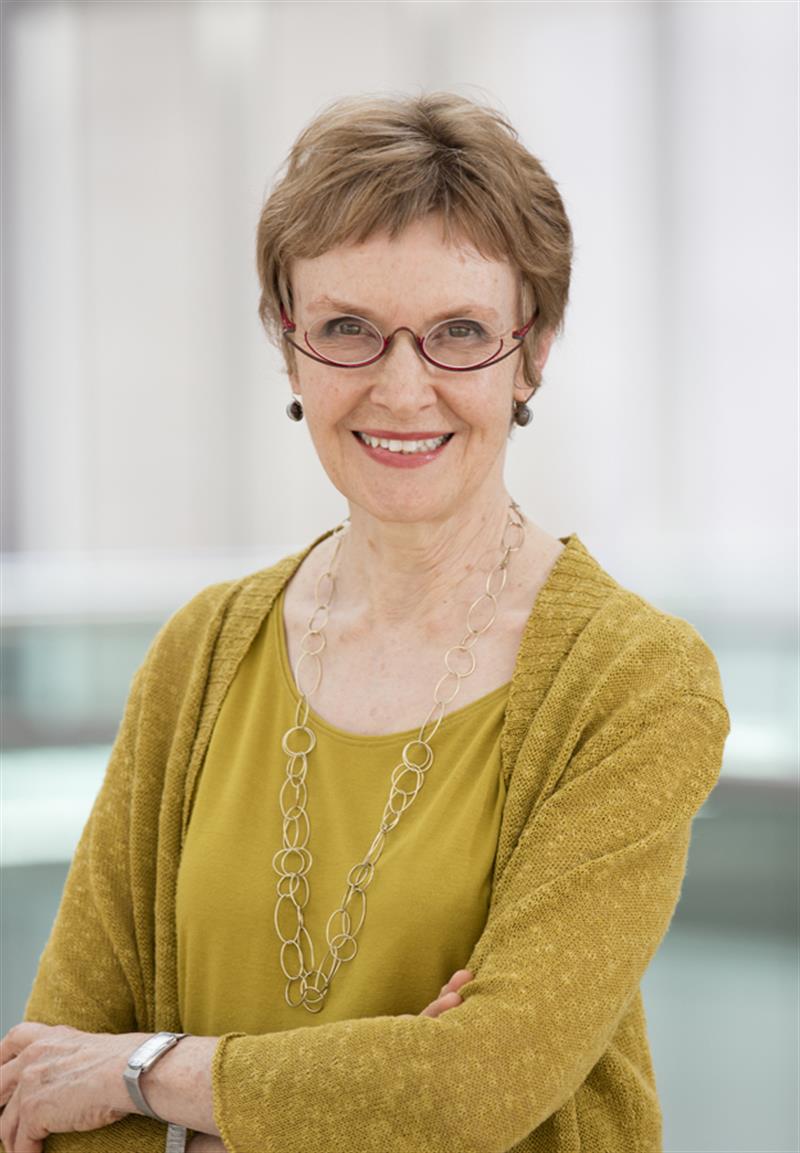 A woman in glasses and a yellow sweater looking directly at the camera.