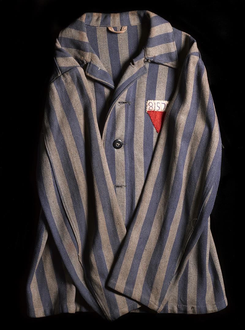 An image of a striped prison uniform with a sewn on number and triangle.