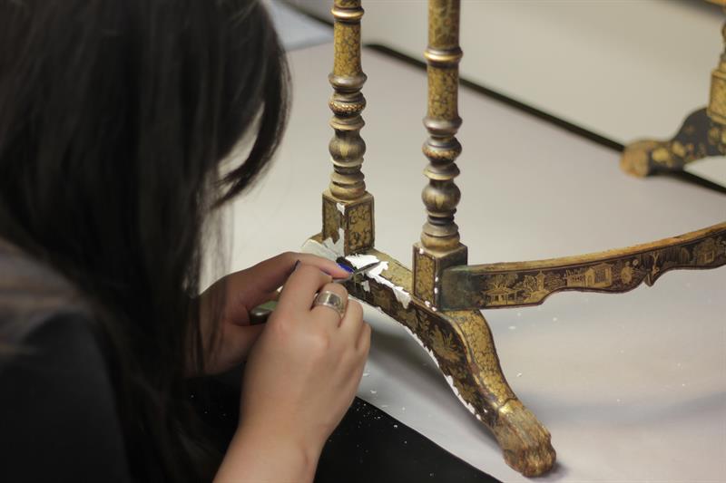 A student uses a small brush to add fill material to losses.