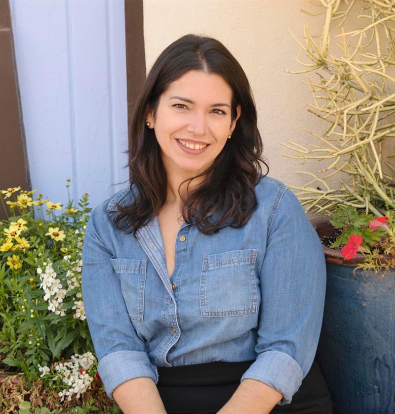 Portrait photo of a woman with long brown hair, wearing a blue shirt.