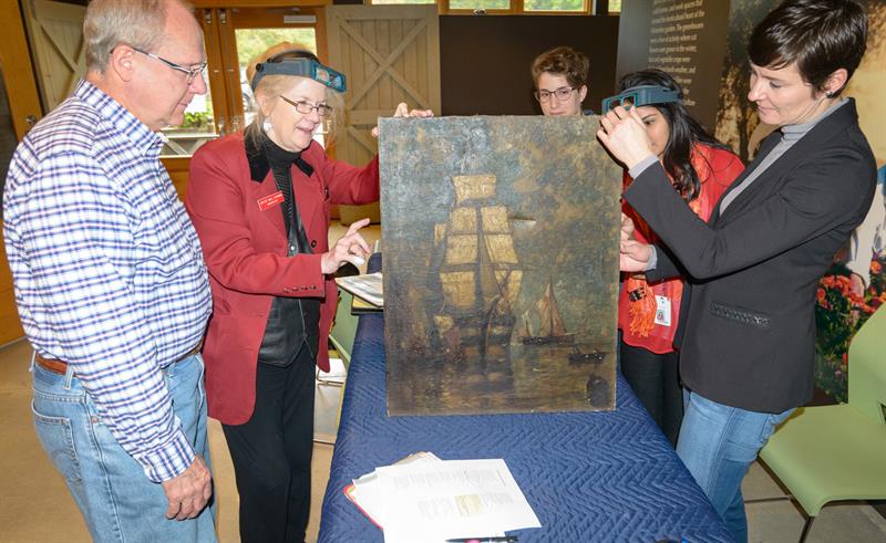Conservators and students look at a painting brought in by the public.