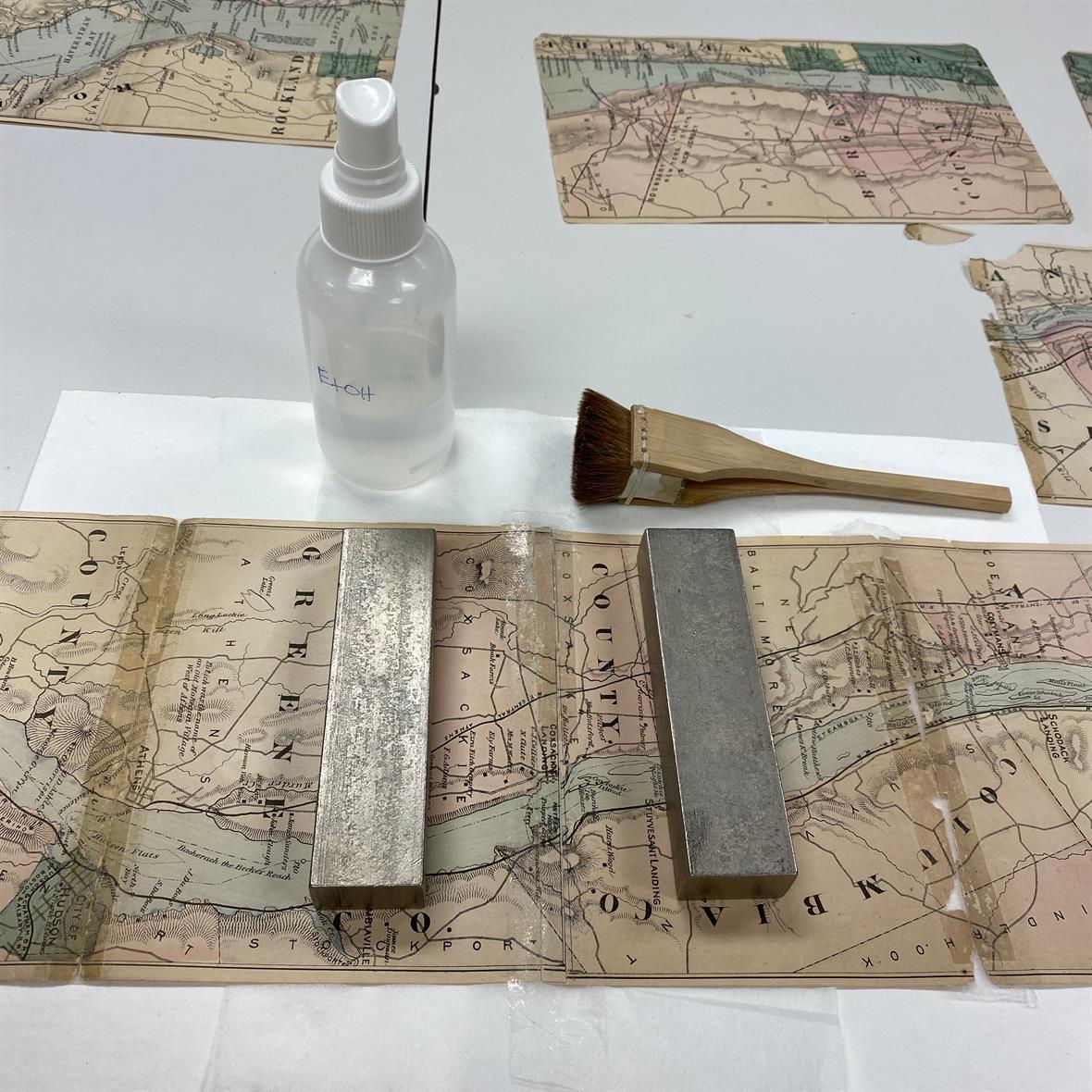 A portion of the map laying on a table, image side up, held in position with weights.