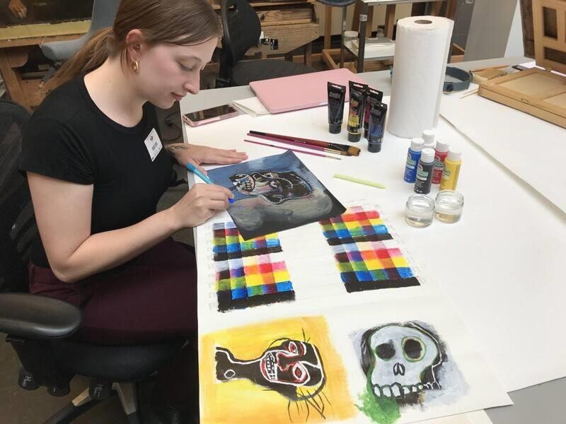 Alumna paints at a table