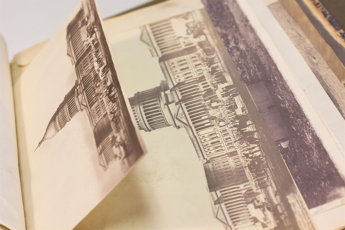 A student lifts a half-page photo in a book, showing the full-page photo underneath. The photos are of the U.S. Capitol dome.