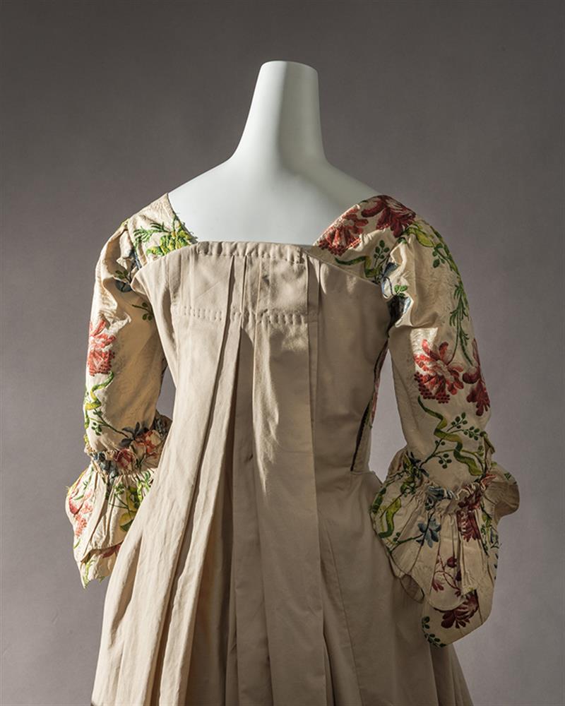 Image of the back of a dress, with folded material draped down the back.