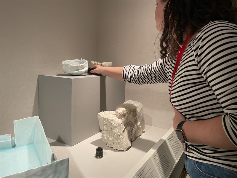 Student places monitors near artworks on pedestals.