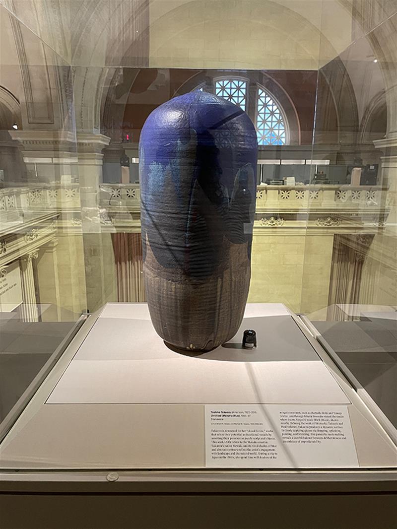 Blue pottery inside a glass vitrine on a museum pedestal.