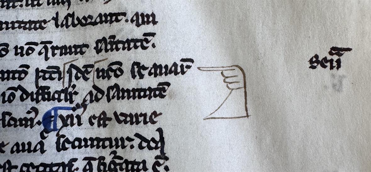 An old manuscript, with a doodle of a hand in the margins that points to a line of text.