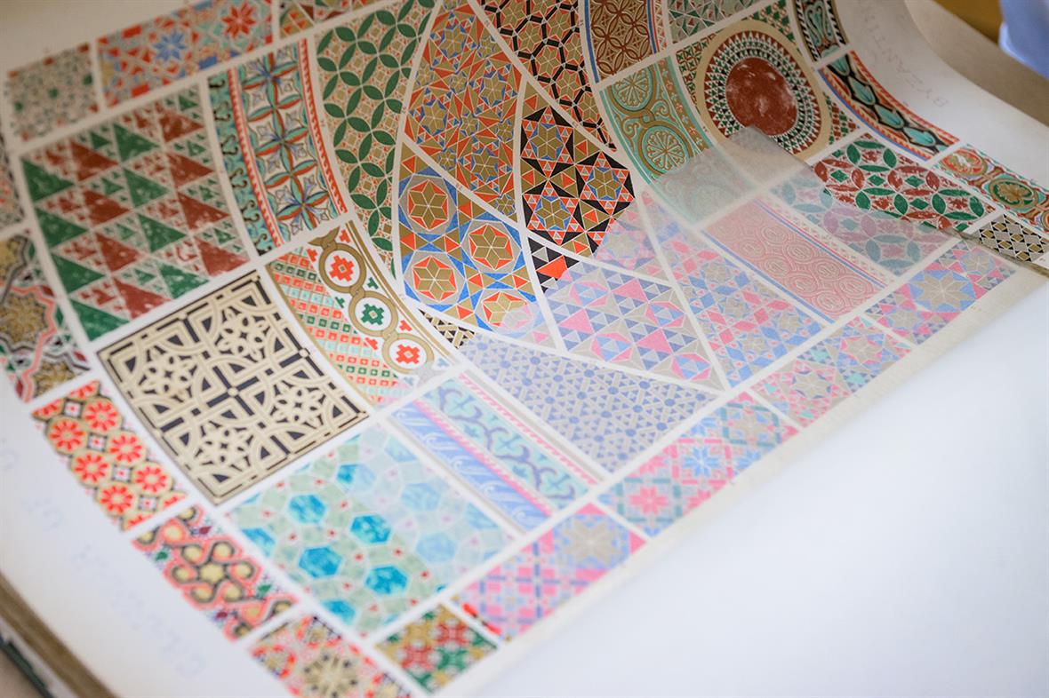A page from the oversized book contains dozens of multicolored geometric designs.