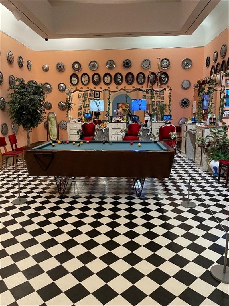 A billiard table in a museum room with brightly colored walls and a checkered floor.