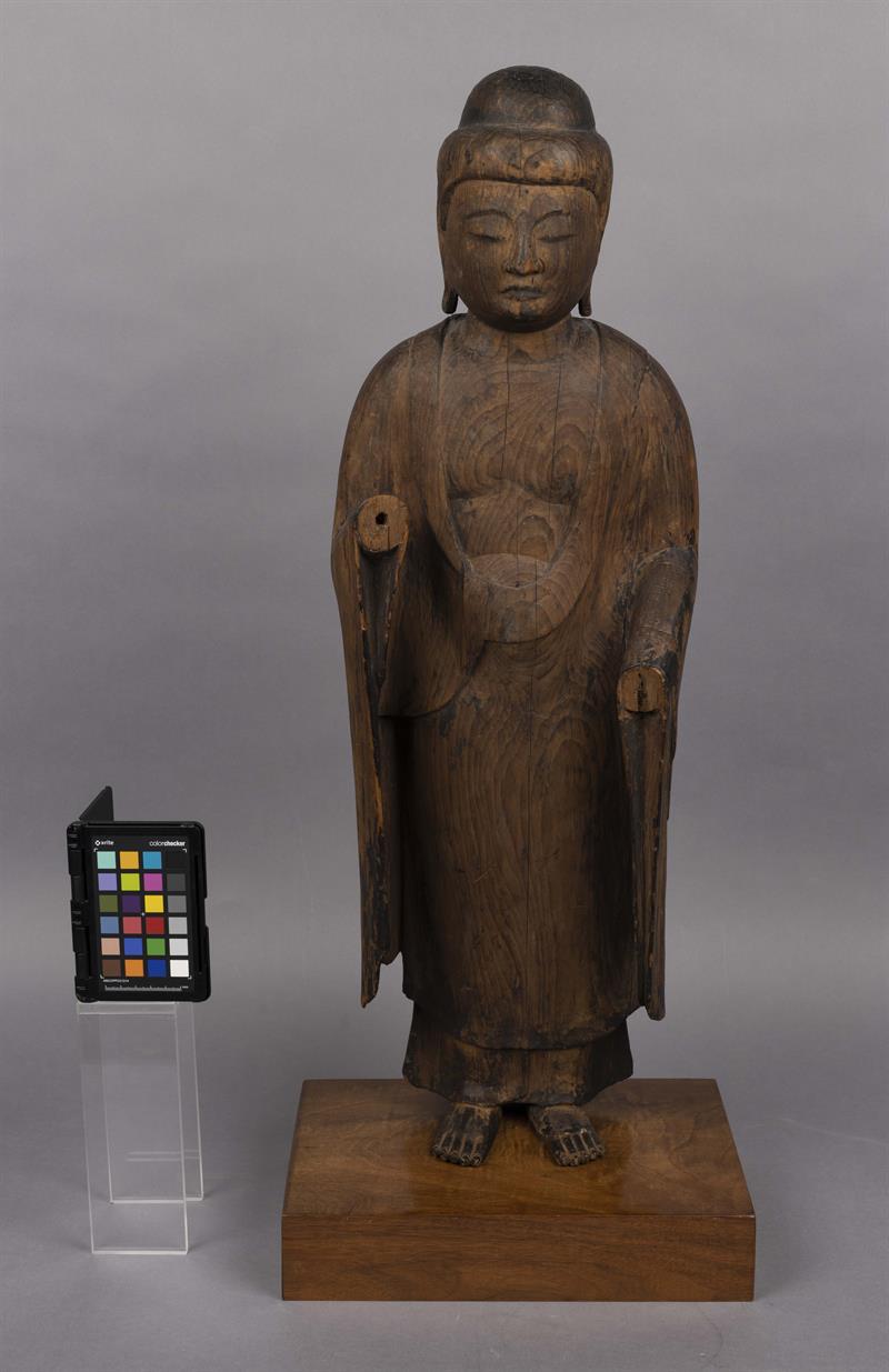Wooden statue of a man in a robe. The statue is old, and is missing its hands.