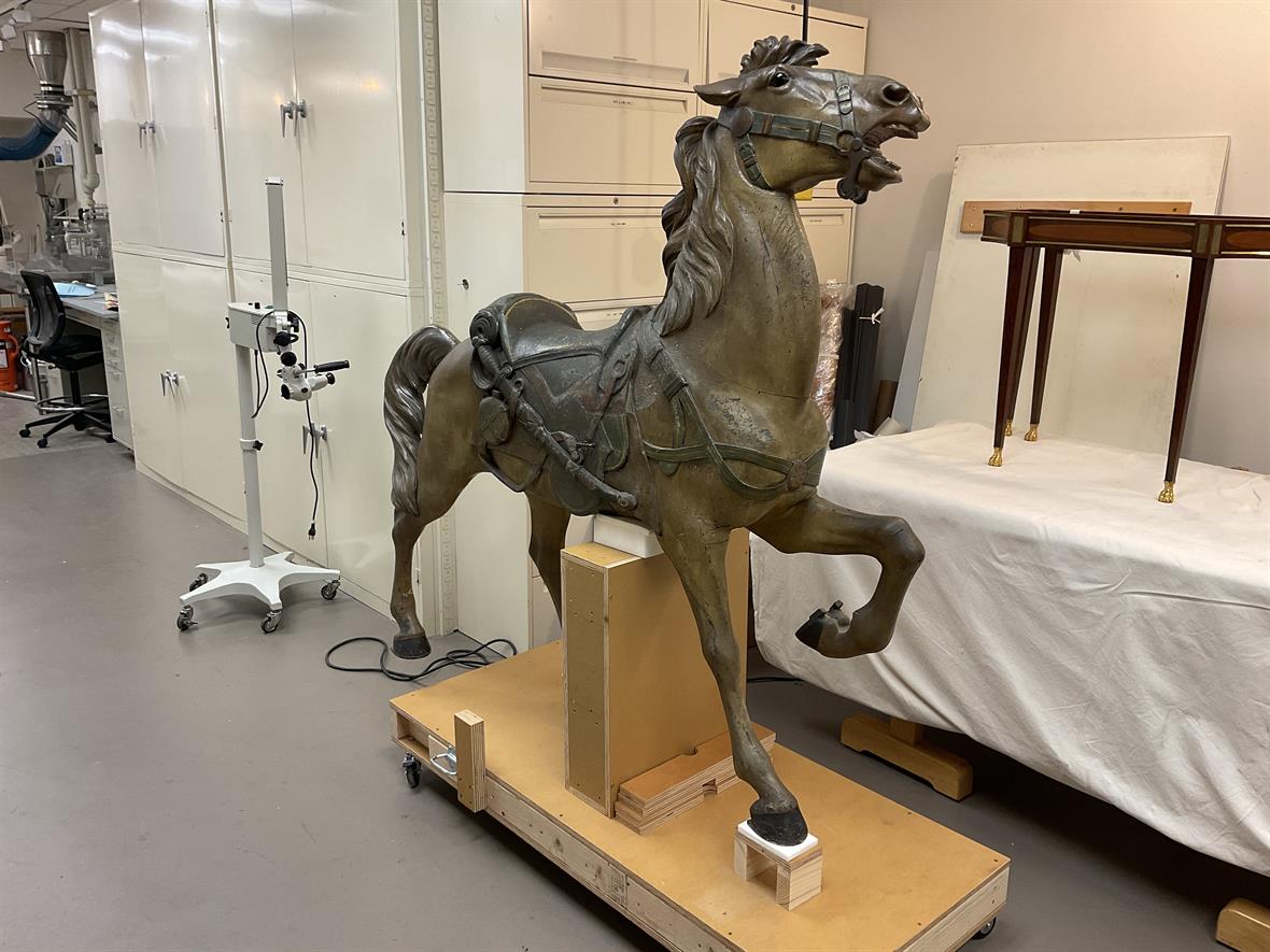 A wooden carousel horse sits inside a conservation lab, waiting for analysis.