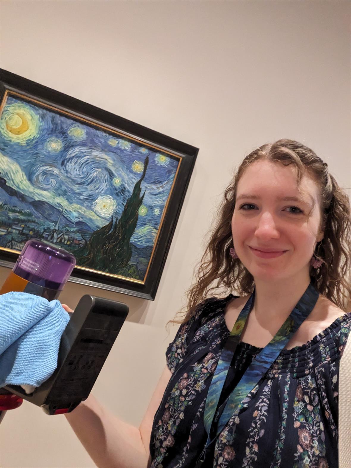A student stand in front a the Starry Night painting by Van Gogh.