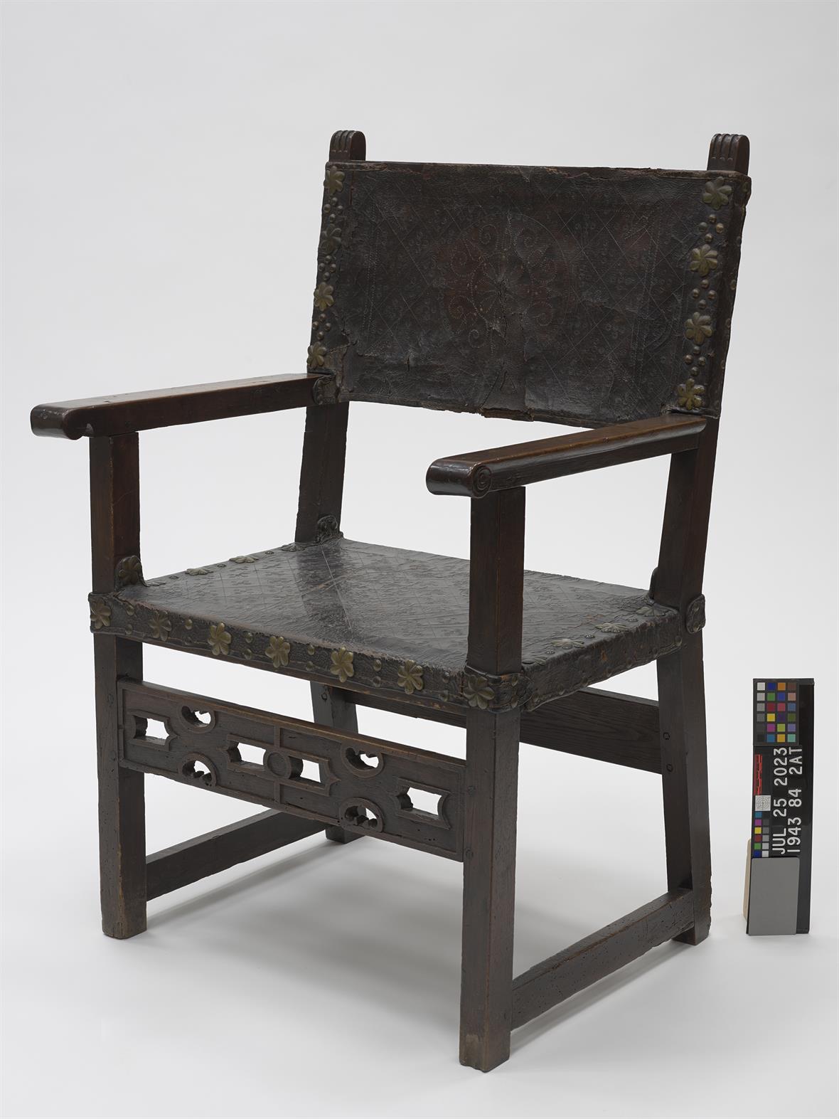Museum documentation image of a wooden chair with aged leather upholstery.