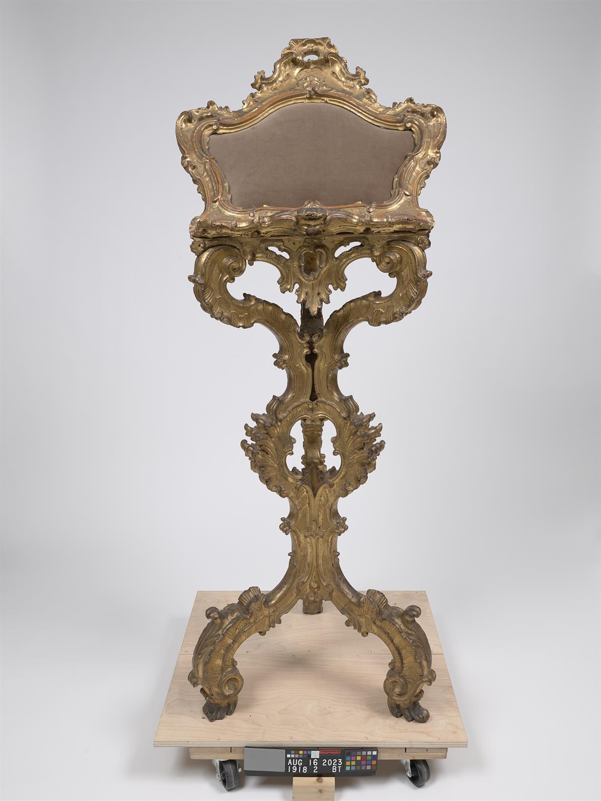 An ornately gilded and carved wooden object sits on a platform.