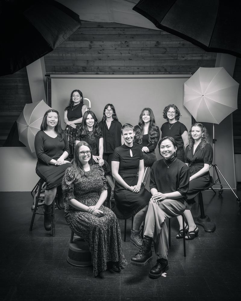 A black and white photo of ten students seated in chairs in a photo studio.