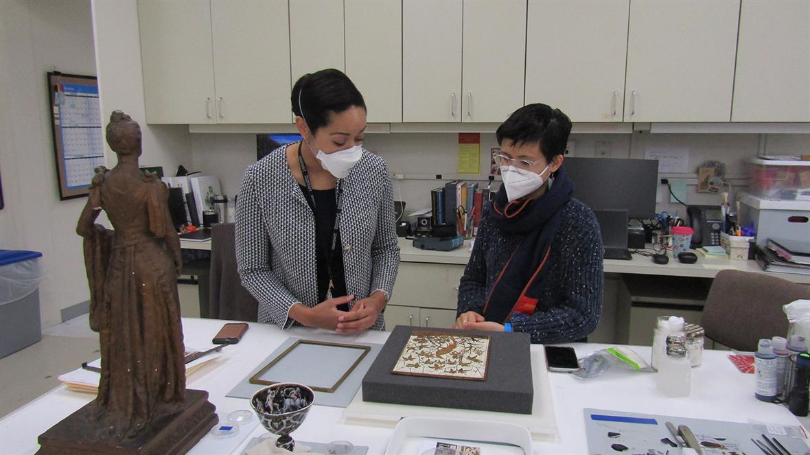 A student and curator stand at a table holding several different collections objects.
