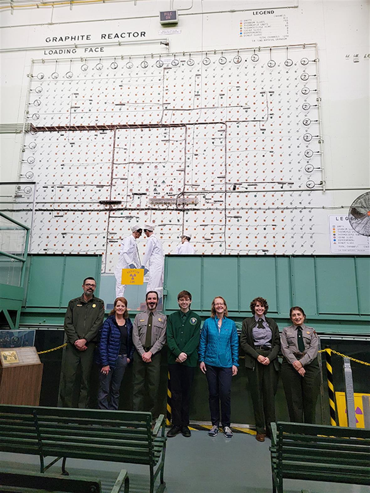 A group of people pose for a picture in front of a display at a historical reactor site.